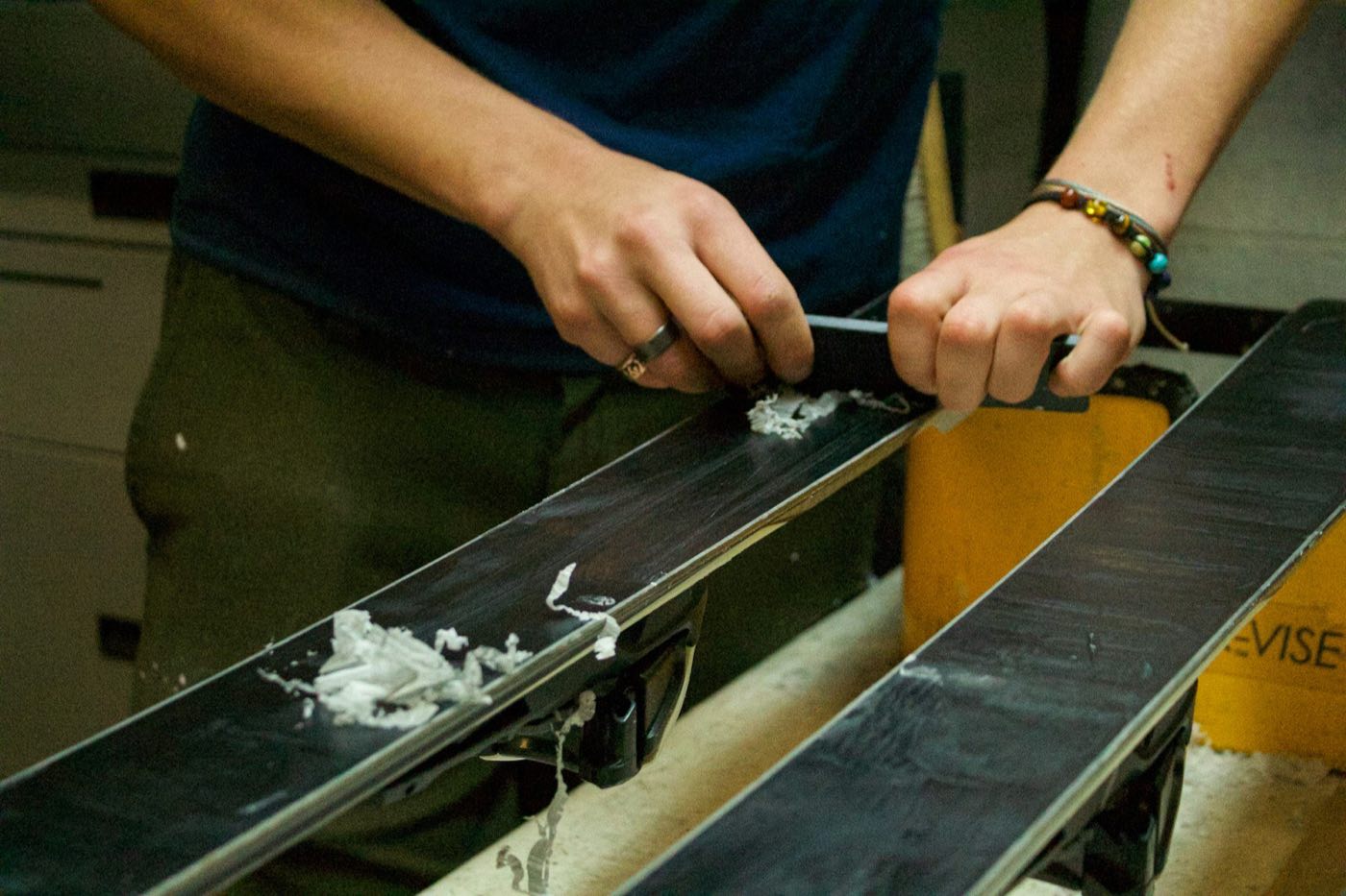 Technician working along a ski base on a workshop bench (stock placeholder)